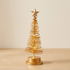 Árvore de Natal dourada com luz LED numa mesa de carvalho claro, junto a uma parede creme
